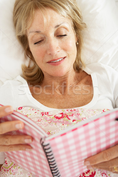 Senior Woman Relaxing In Bed Reading Diary Stock photo © monkey_business