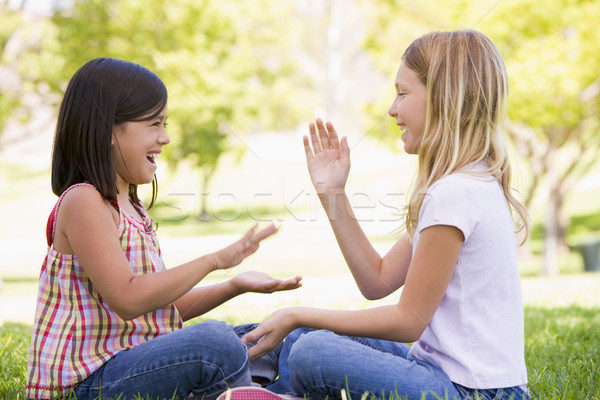 Two young girl friends sitting outdoors playing patty cake smili Stock photo © monkey_business