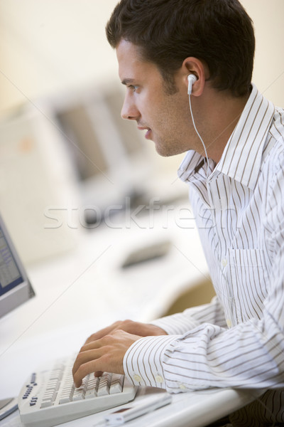 Man in computer room listening to MP3 player while typing Stock photo © monkey_business