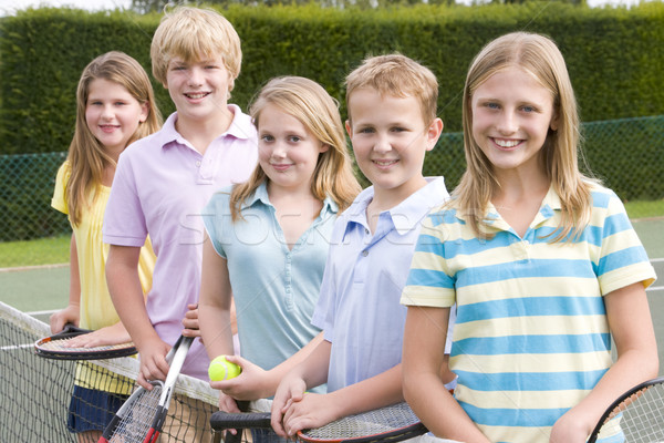 Five young friends with rackets on tennis court smiling Stock photo © monkey_business