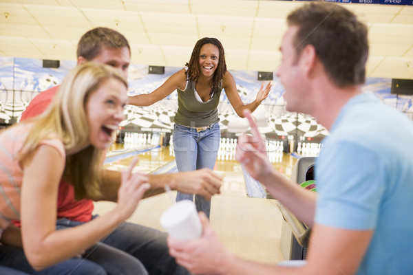 Four young adults laughing and gesturing in a bowling alley Stock photo © monkey_business