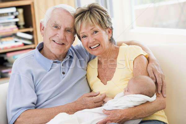 Stock photo: Grandparents in living room with baby smiling