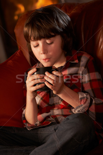 Stock photo: Young Boy Relaxing With Hot Drink By Cosy Log Fire