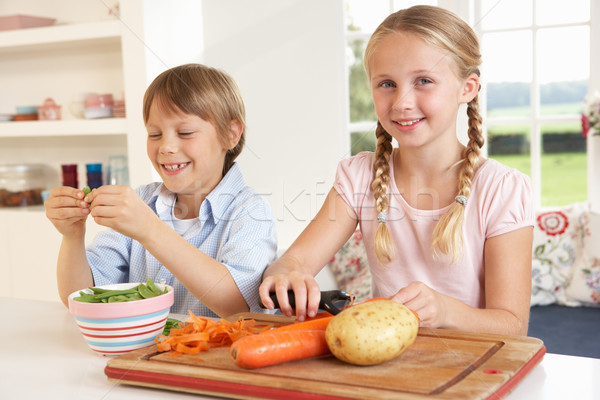 Happy children peeling vegetables in kitchen Stock photo © monkey_business
