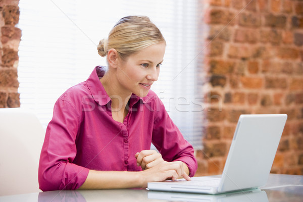 Businesswoman sitting in office using laptop smiling Stock photo © monkey_business