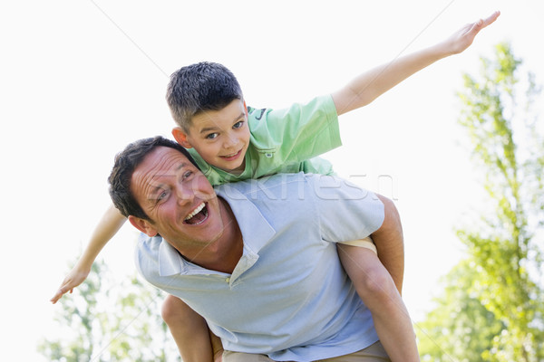Man giving young boy piggyback ride outdoors smiling Stock photo © monkey_business