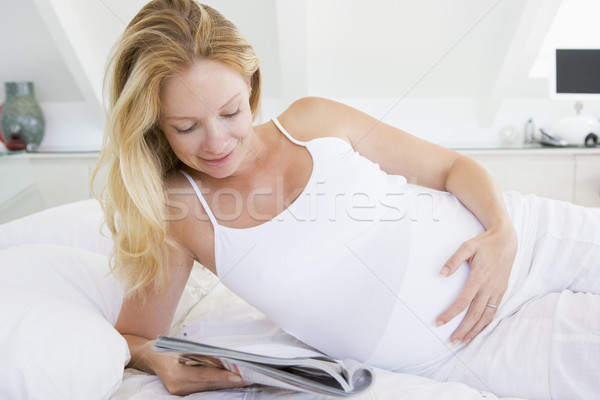Foto d'archivio: Donna · incinta · letto · lettura · magazine · sorridere · felice