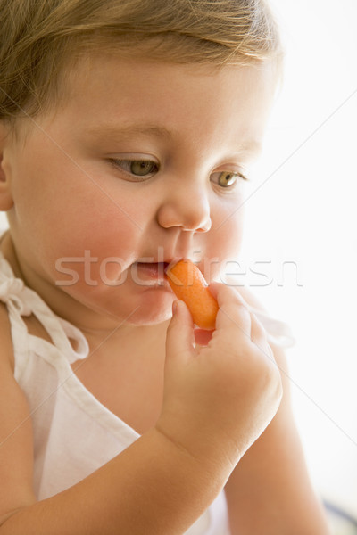 Baby indoors eating carrot. Stock photo © monkey_business