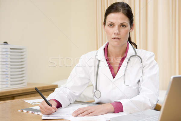 Doctor with laptop writing in doctor's office Stock photo © monkey_business