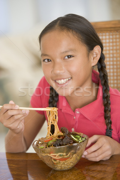 Stock photo: Young girl in dining room eating chinese food smiling