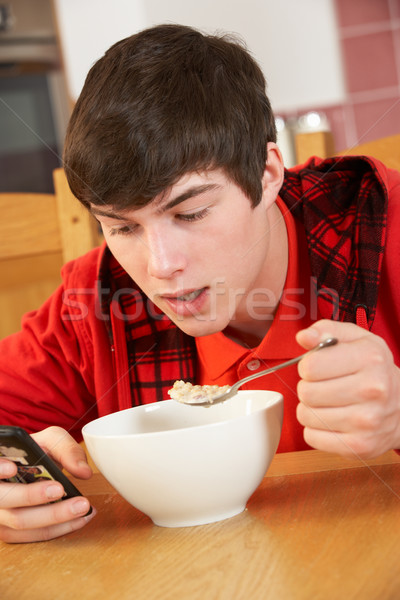 Tizenéves fiú tini sms chat eszik reggeli telefon Stock fotó © monkey_business
