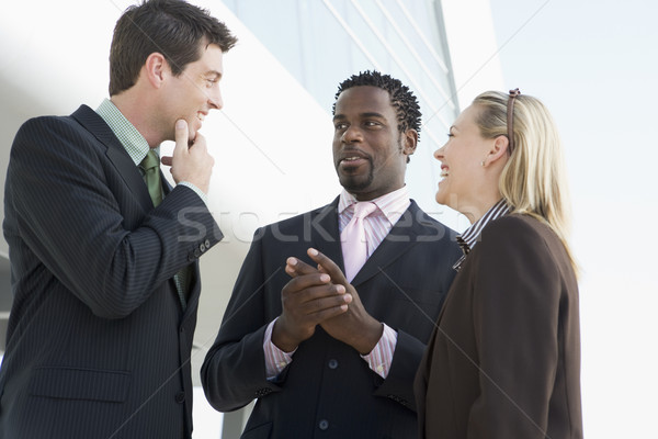 Stock photo: Three businesspeople standing outdoors by building talking and s
