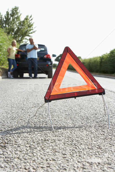 Stock photo: Couple Broken Down On Country Road With Hazard Warning Sign In F