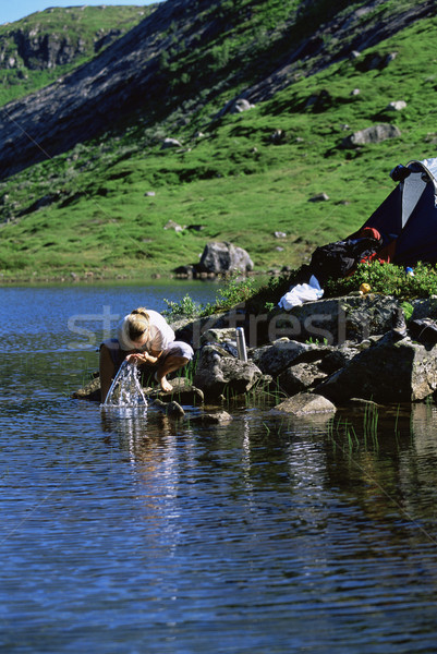 Young woman washing clothes in lake next to tent Stock photo © monkey_business