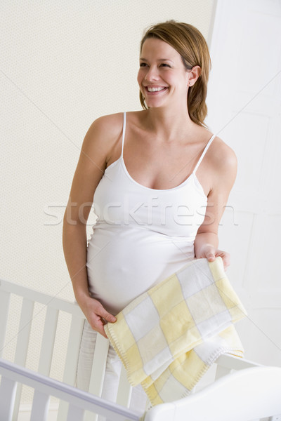 Stock photo: Pregnant woman setting up baby crib smiling