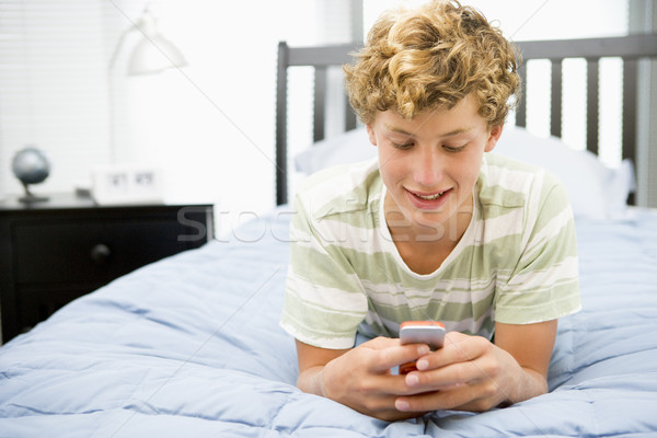 Tizenéves fiú ágy mobiltelefon telefon boldog mobil Stock fotó © monkey_business