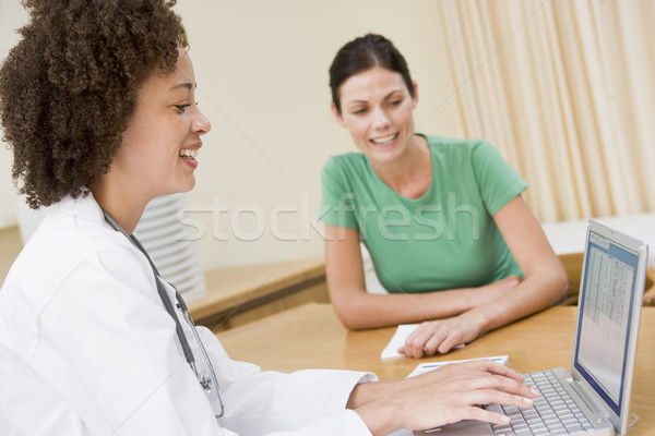 Doctor using laptop with woman in doctor's office smiling Stock photo © monkey_business