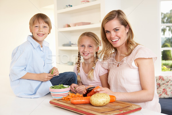 Young mother with children peeling vegetables in kitchen Stock photo © monkey_business