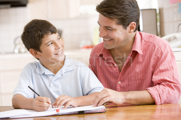Man helping young boy in kitchen doing homework and smiling Stock photo © monkey_business