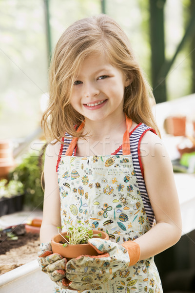 Young girl in greenhouse holding potted plant smiling Stock photo © monkey_business