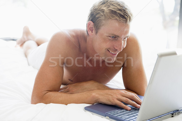 Man lying in bed with laptop smiling Stock photo © monkey_business