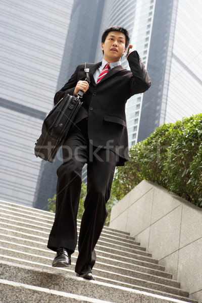 Chinese Businessman Rushing Down Steps On Mobile Phone Stock photo © monkey_business