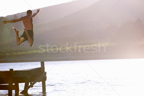 [[stock_photo]]: Jeune · homme · sautant · lac · eau · homme · coucher · du · soleil