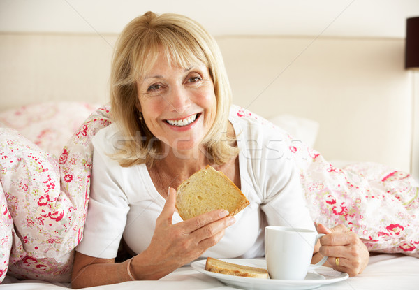 Senior Woman Snuggled Under Duvet Eating Breakfast Stock photo © monkey_business