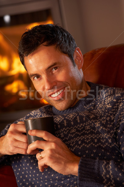 Middle Aged Man Relaxing With Hot Drink By Cosy Log Fire Stock photo © monkey_business