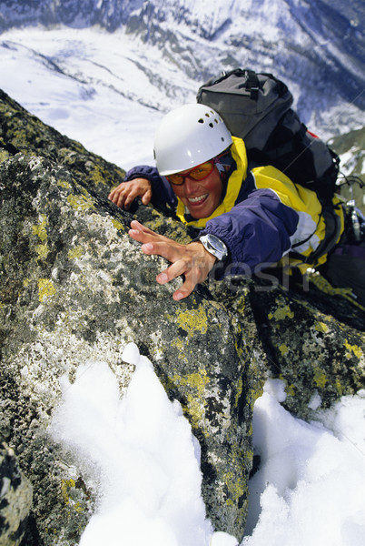 Mountaineer climbing snowy rock face Stock photo © monkey_business