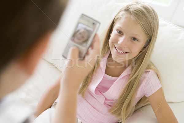 Stock photo: Young boy taking picture of smiling young girl with camera phone