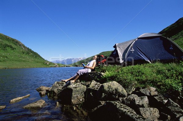 Young woman relaxing on rocks next to lake Stock photo © monkey_business