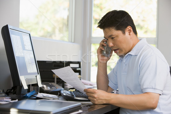 Stock photo: Man in home office with computer and paperwork on telephone
