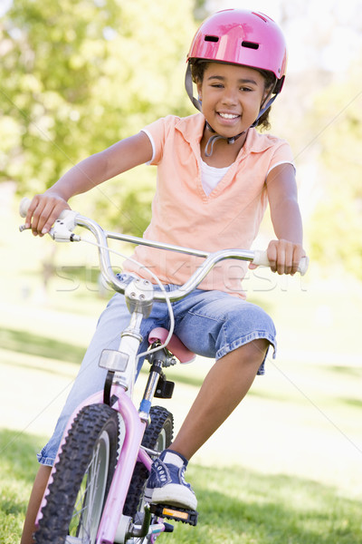 Stock photo: Young girl on bicycle outdoors smiling