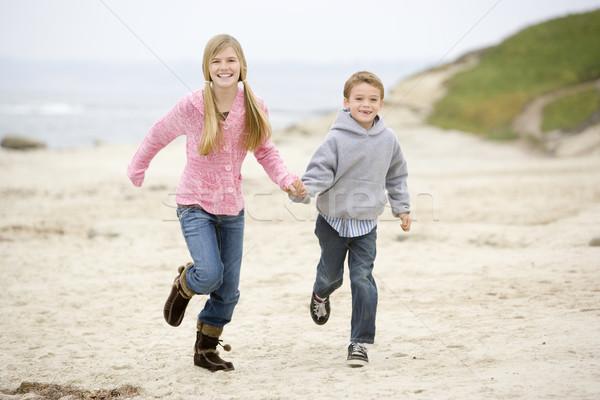 Two young children running on beach holding hands smiling Stock photo © monkey_business
