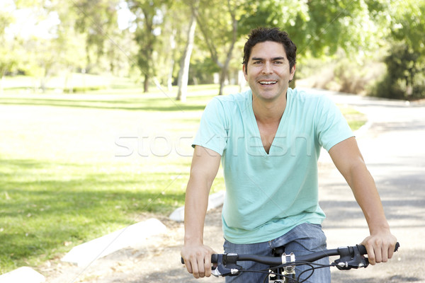 ストックフォト: 若い男 · ライディング · 自転車 · 公園 · 笑顔 · 肖像