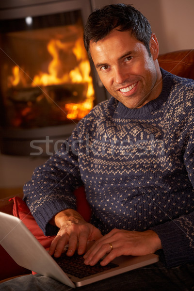 Middle Aged Man Using Laptop Computer By Cosy Log Fire Stock photo © monkey_business