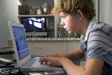 Młody chłopak sypialni za pomocą laptopa słuchania mp3 Zdjęcia stock © monkey_business