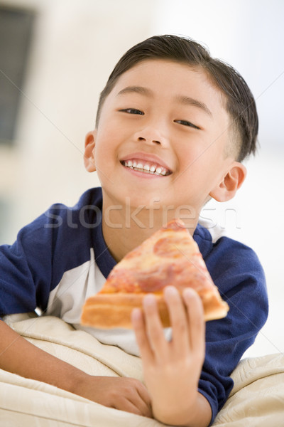 Young boy eating pizza slice in living room smiling Stock photo © monkey_business