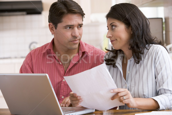 Couple in kitchen with paperwork using laptop looking unhappy Stock photo © monkey_business