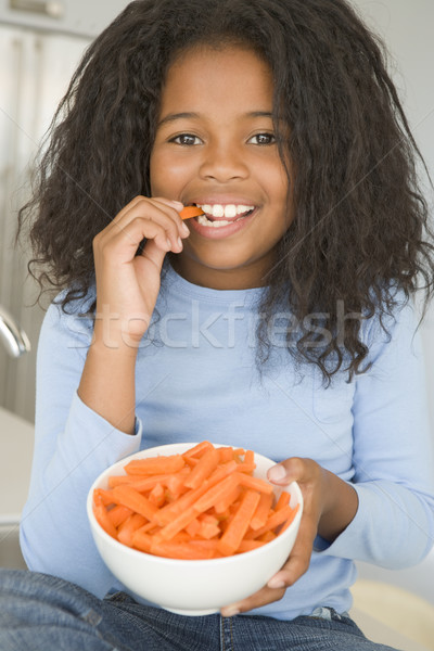 Fiatal lány konyha eszik sárgarépa mosolyog lány Stock fotó © monkey_business