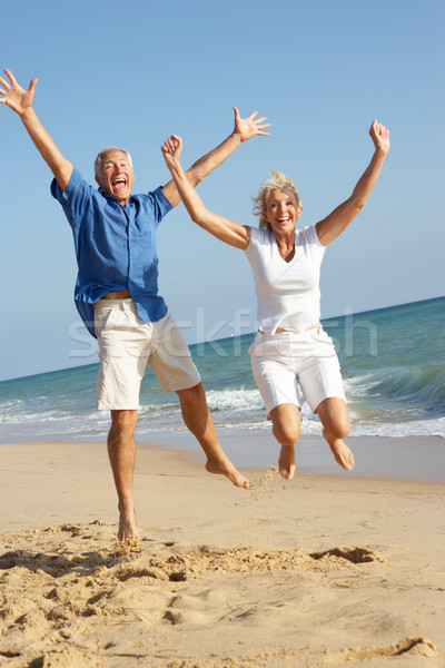 Senior Couple Enjoying Beach Holiday Jumping In Air Stock photo © monkey_business