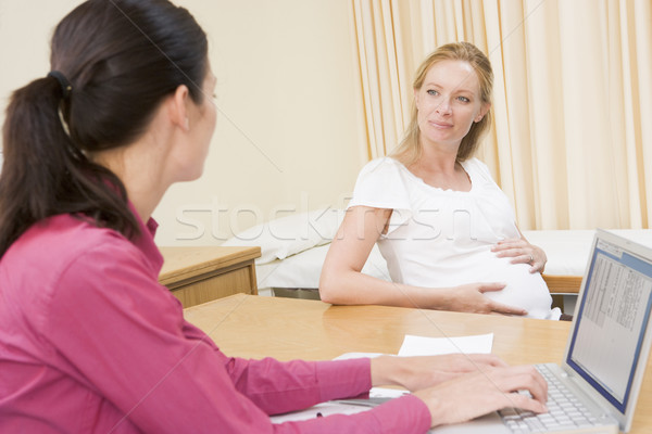 Doctor with laptop and pregnant woman in doctor's office smiling Stock photo © monkey_business