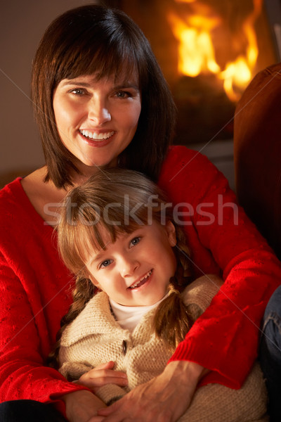 Mother And Daughter Relaxing On Sofa By Cosy Log Fire Stock photo © monkey_business