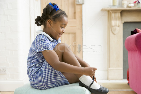 Stock photo: Young girl in front hallway fixing shoe and smiling