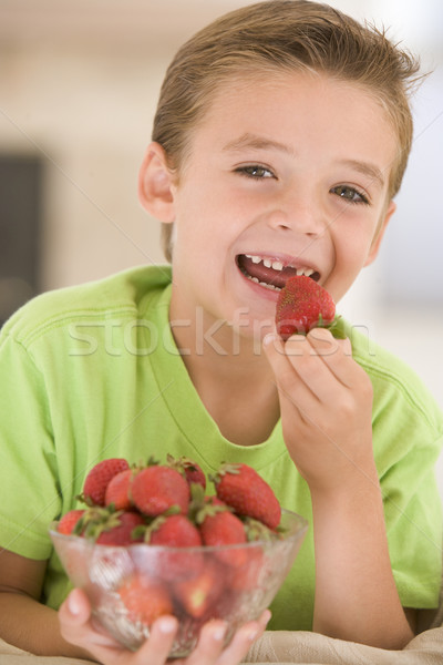 Stock photo: Young boy eating strawberries in living room smiling