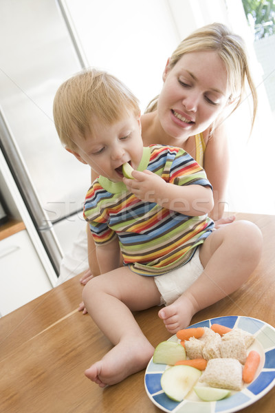 Mother and baby in kitchen eating fruit and vegetables Stock photo © monkey_business