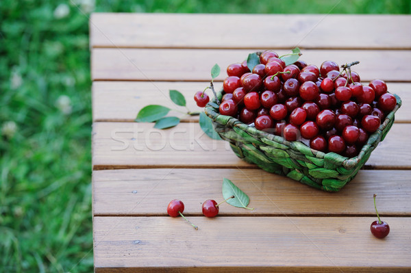 Stock photo: Juicy ripe cherries in a basket on wooden table outdoor