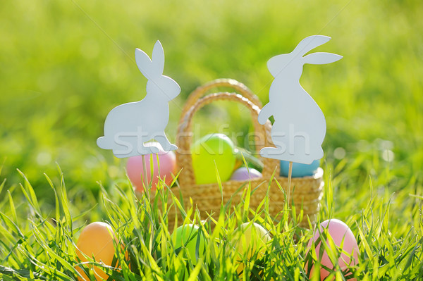 Stock photo: Coloured Easter Eggs In A Basket Padded Out With Rabbit Decorations