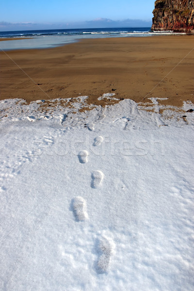 Stock photo: footprint tracks in snow on empty beach on a cold winters day
